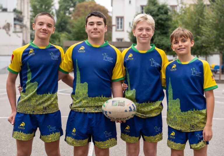 Un groupe d’élèves en maillot de rugby pose avec un ballon.