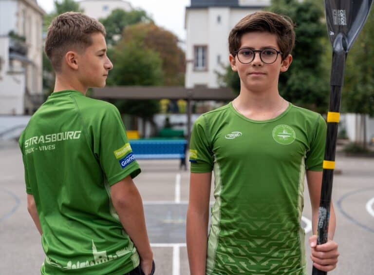 Deux élèves en tenue du club de canoë-kayak, l’un tenant une pagaie.